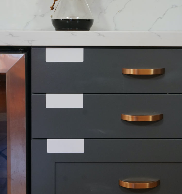 White TidyPop label clips on cabinet doors