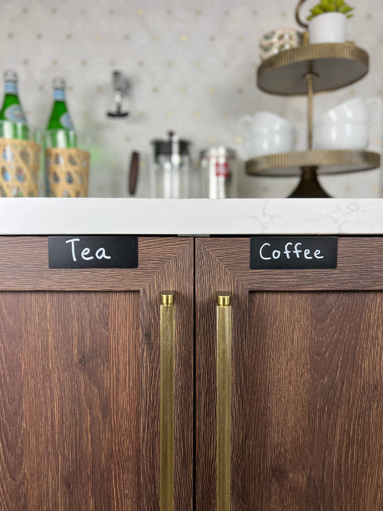 Black TidyPop labels reading Tea and Coffee on walnut cabinet doors with brass pulls