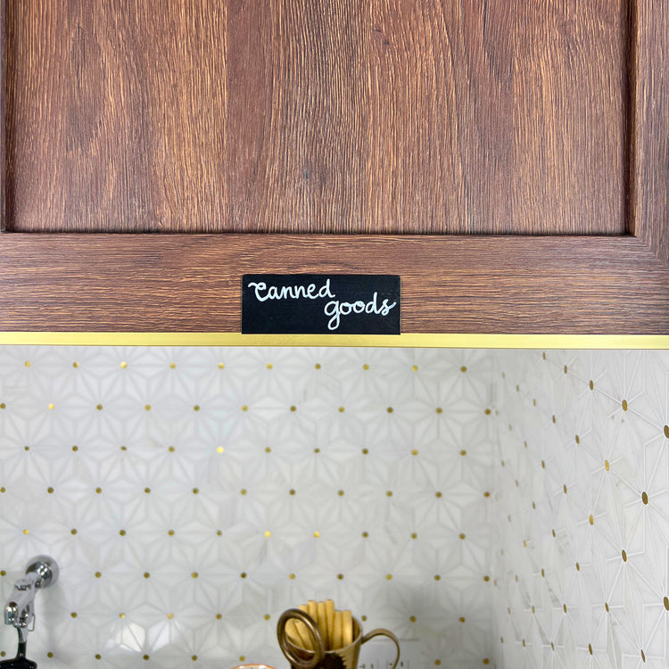Black TidyPop label that says canned goods on a wood cabinet
