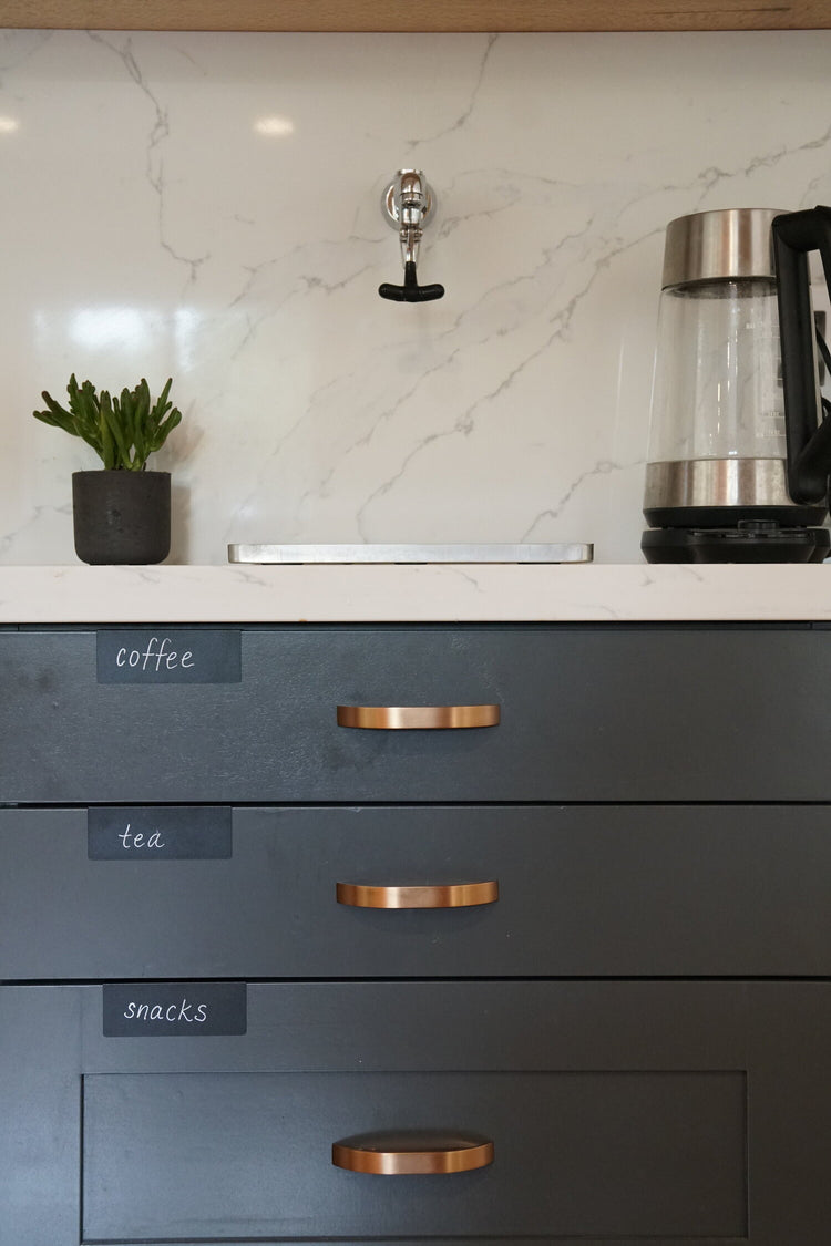 TidyPop clips reading coffee, tea, and snacks on charcoal drawers under a marble counter