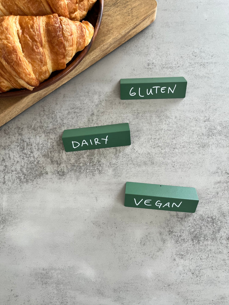 Green place cards labeled gluten, dairy and vegan next to croissants