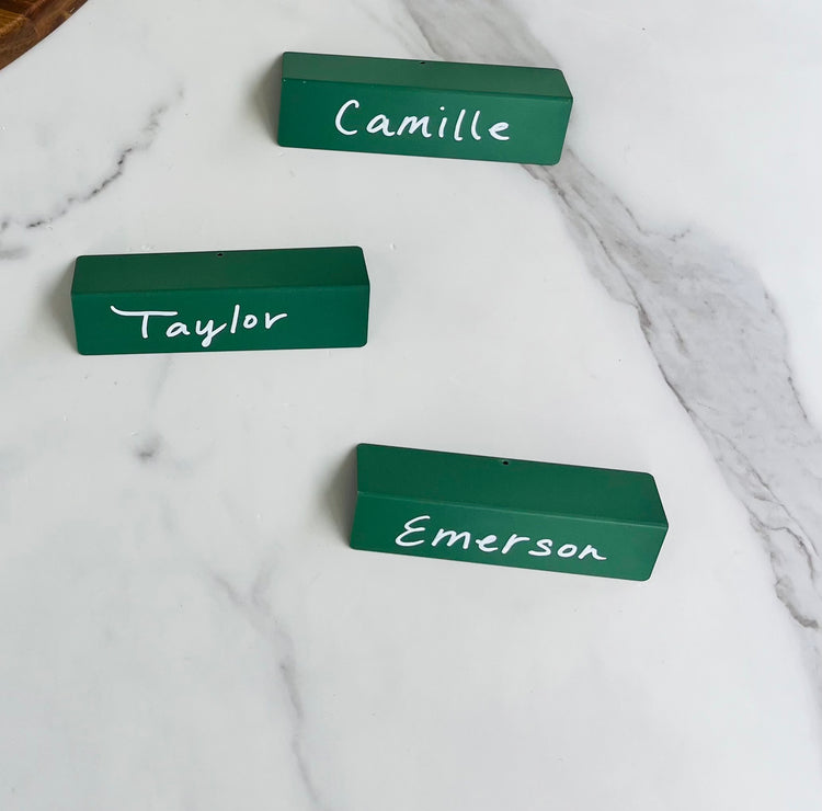 Sage TidyPop place cards that say Camille, Taylor, and Emerson on marble